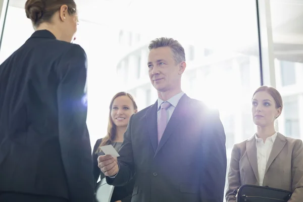 Affärsman ger sitt kort till kvinnliga medarbetare — Stockfoto