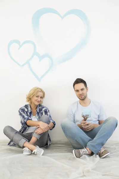 Couple with painted hearts on wall — Stock Photo, Image