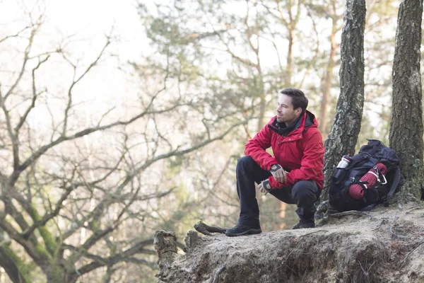 Hiker crouching on cliff — Stock Photo, Image