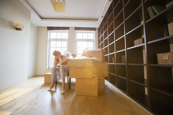 Женщина сидит за картонными коробками
