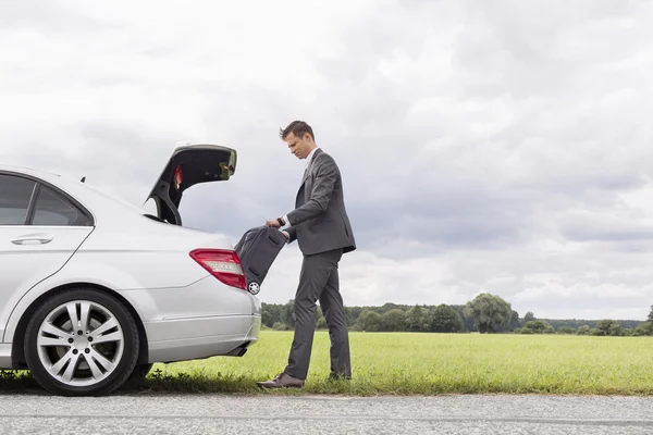 Geschäftsmann nimmt Koffer aus Auto — Stockfoto