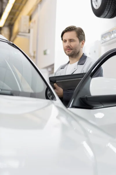 Ingénieur tenant PC tout en examinant la voiture — Photo