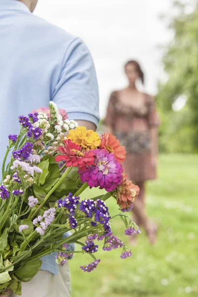 Man surprising woman with bouquet — Stock Photo, Image