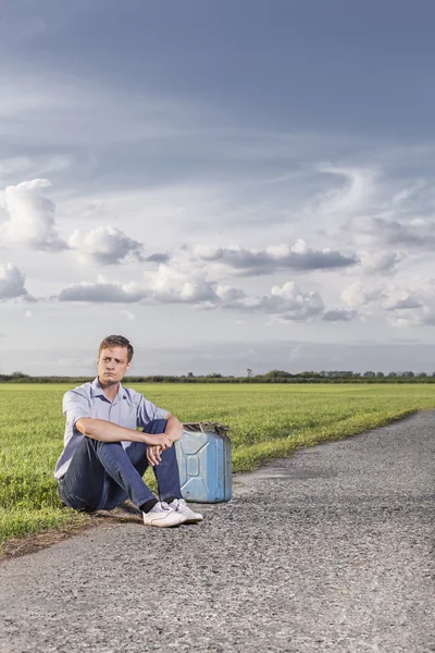 Чоловік сидить на сільській дорозі — стокове фото