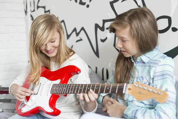 Fille écoute soeur jouer de la guitare — Photo