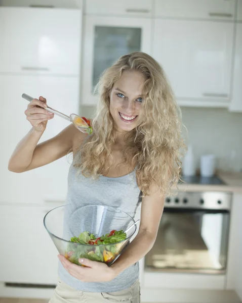 Vrouw mengen salade in keuken — Stockfoto