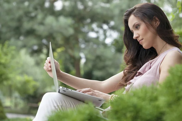 Femme utilisant un ordinateur portable dans le parc — Photo