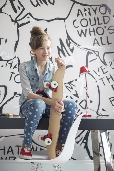 Mädchen mit Skateboard sitzt auf Tisch — Stockfoto