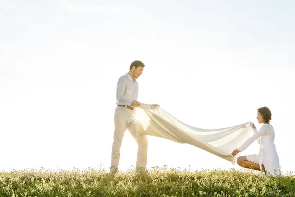 Woman and man spreading picnic blanket — Stock Photo, Image