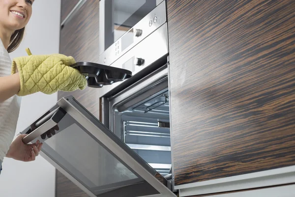 Mujer quitando plato del horno — Foto de Stock