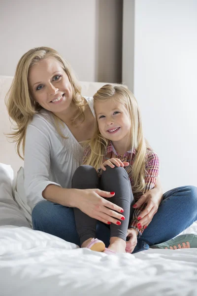 Mother and daughter sitting on bed — Stock Photo, Image