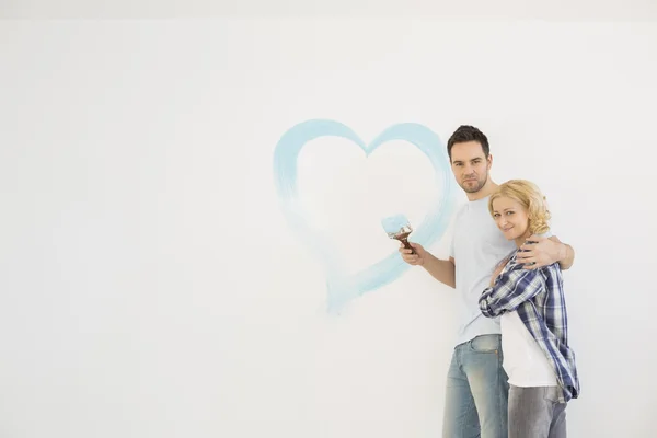 Couple with painted heart on wall — Stock Photo, Image