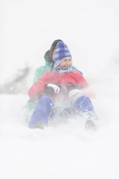 Young couple sledding in snow — Stock Photo, Image