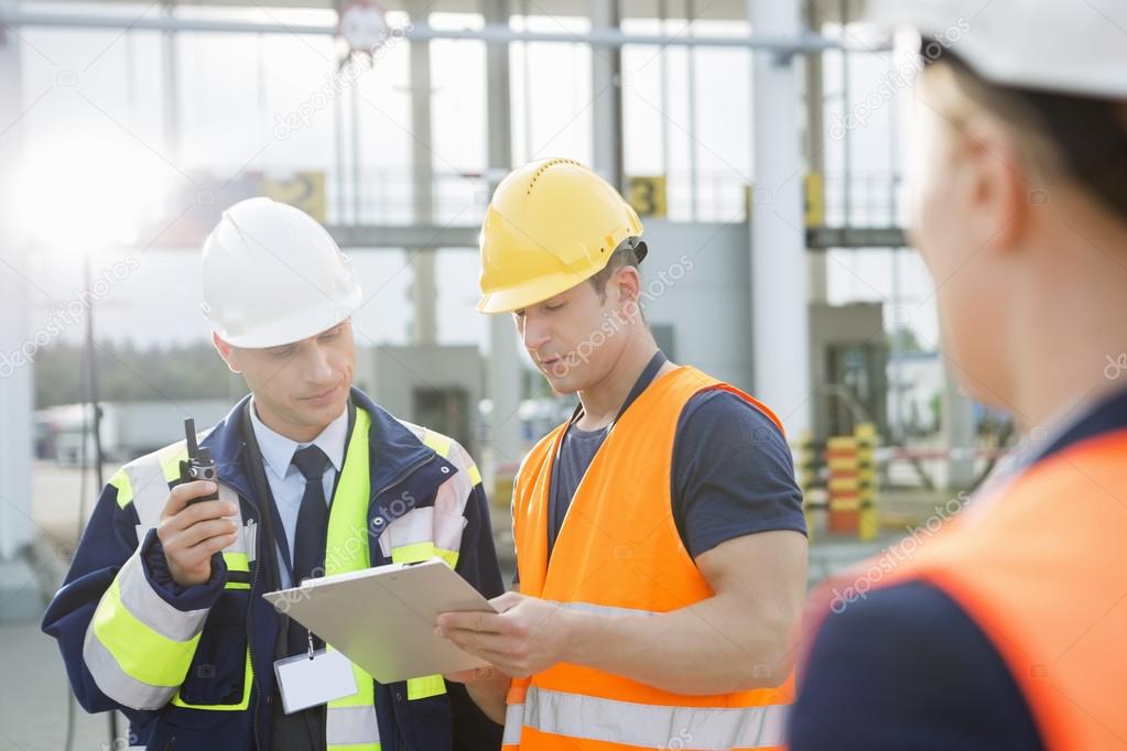 Workers discussing over clipboard