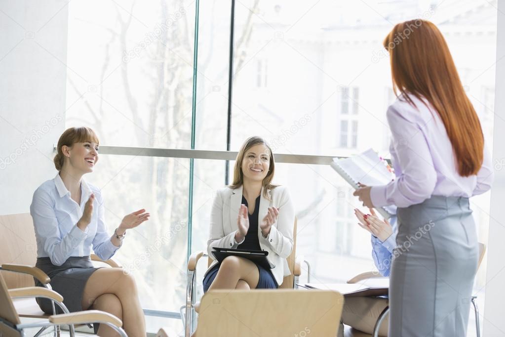 Businesswomen clapping for colleague