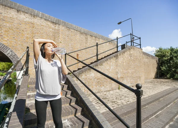 Woman drinking water on stairs — Stock Photo, Image