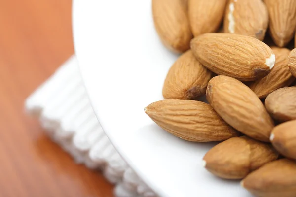 Almonds on white plate — Stock Photo, Image