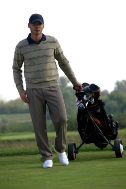 golf çantası ile arabası taşıyan adam