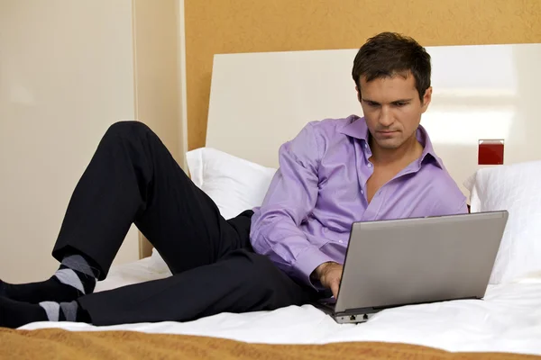 Man met laptop op bed — Stockfoto