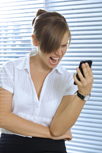 Dühös üzletasszony látszó-on egy mozgatható telefon — Stock Fotó