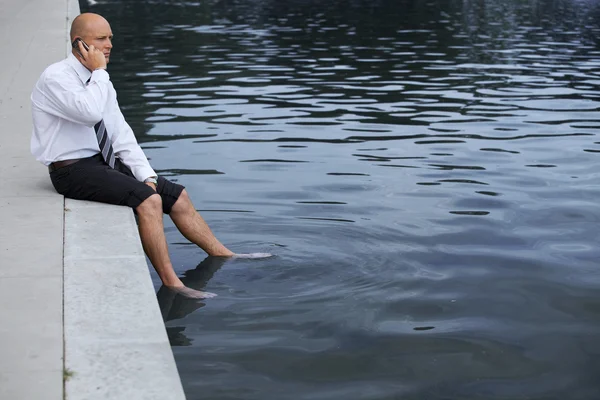 Geschäftsmann sitzt auf Mauer am See — Stockfoto