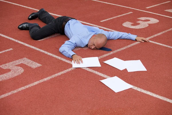 Empresário deitado em uma pista de corrida — Fotografia de Stock