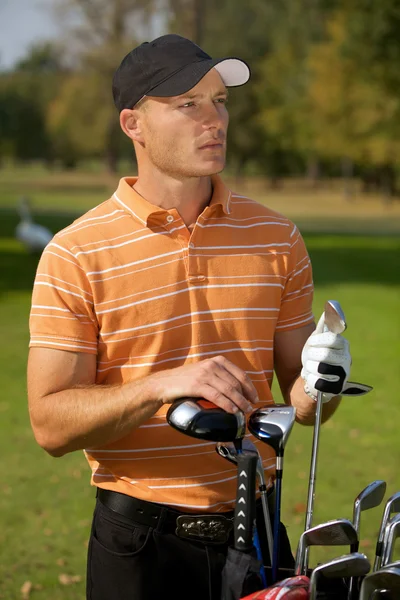 Jeune homme debout près du sac de golf — Photo