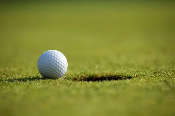 Bola de golfe perto de buraco — Fotografia de Stock