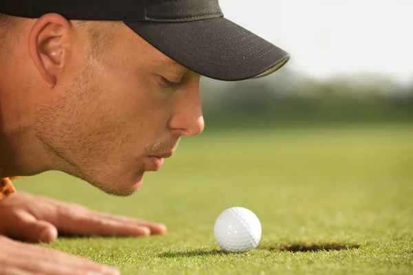 Homme soufflant sur la balle de golf — Photo