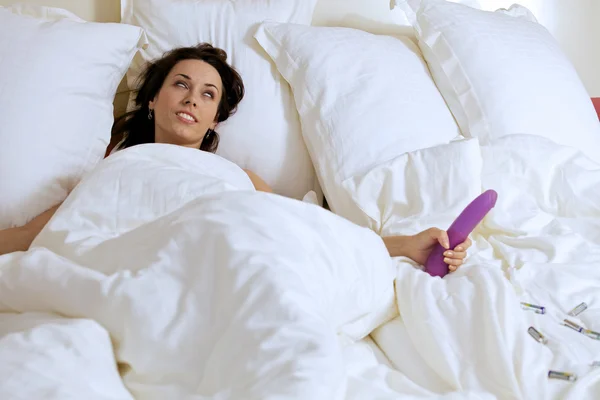 Frau hält Dildo auf Bett — Stockfoto