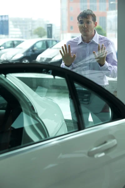 Muž zvědavě při pohledu na nové auto — Stock fotografie