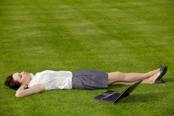 Businesswoman lying in park — Stock Photo, Image