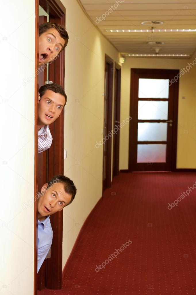 Businessmen peeking out of door