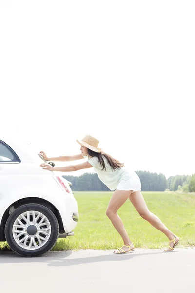 女性ダウン壊れた車を押す — ストック写真