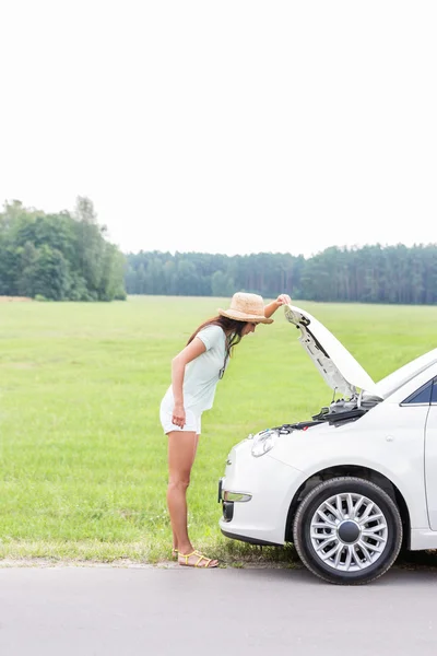 Kadın aşağı kırık araba incelenmesi — Stok fotoğraf
