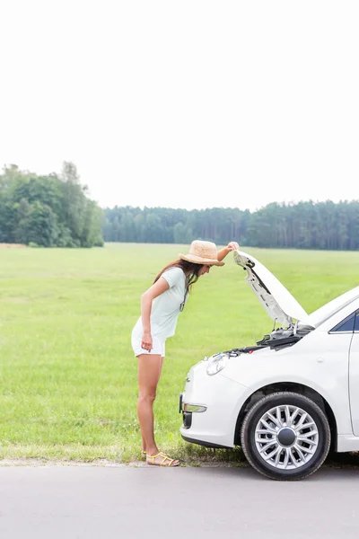 Žena zkoumání porouchaný auta — Stock fotografie