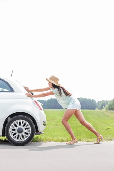 女性ダウン壊れた車を押す — ストック写真