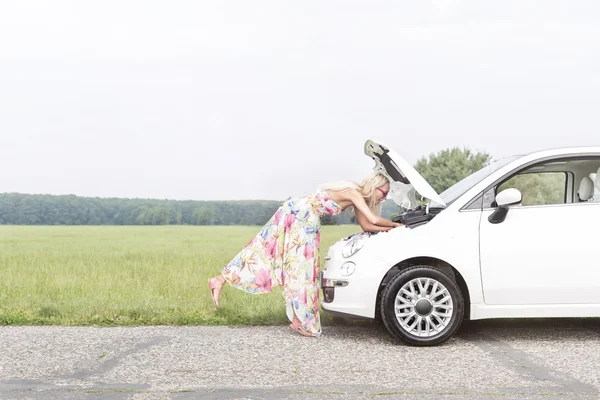 女性ダウン壊れた車を調べる — ストック写真