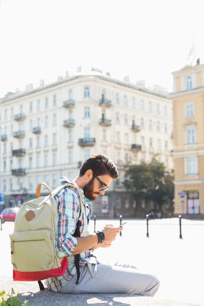 Muž s batohem pomocí mobilního telefonu — Stock fotografie