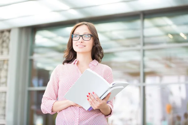 Frau schaut weg, während sie Bücher hält — Stockfoto