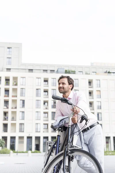 Businessman leaning on bicycle — Stock Photo, Image