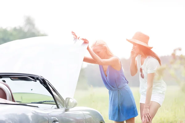 Friends examining broken down car — Stock Photo, Image