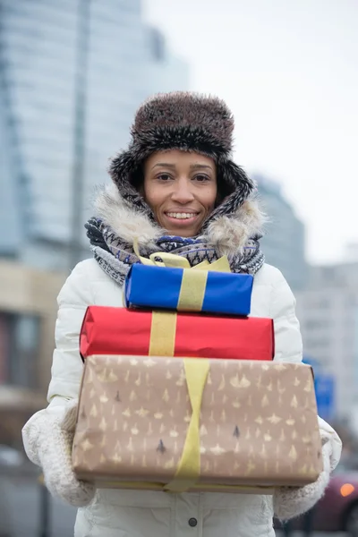 Woman carrying stacked gifts — Stock Photo, Image