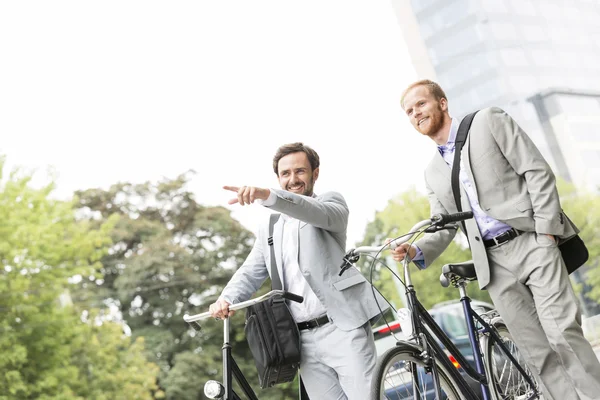 Homem de negócios com bicicleta mostrando algo — Fotografia de Stock