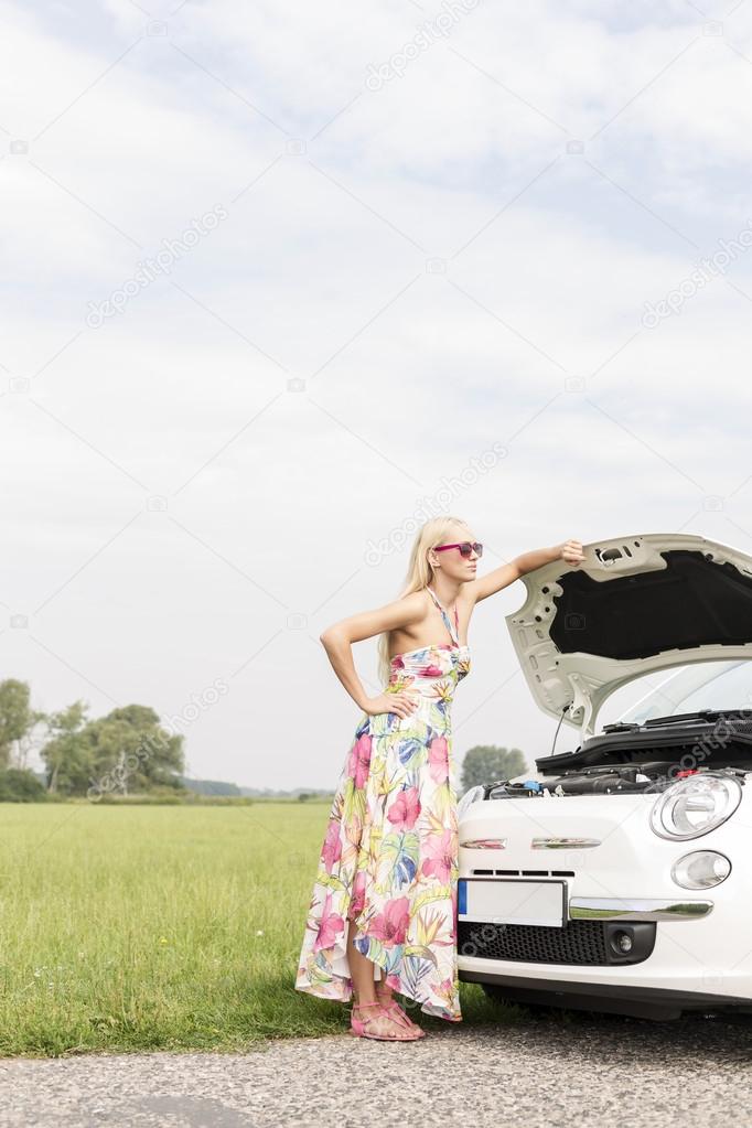 woman standing by broken down car