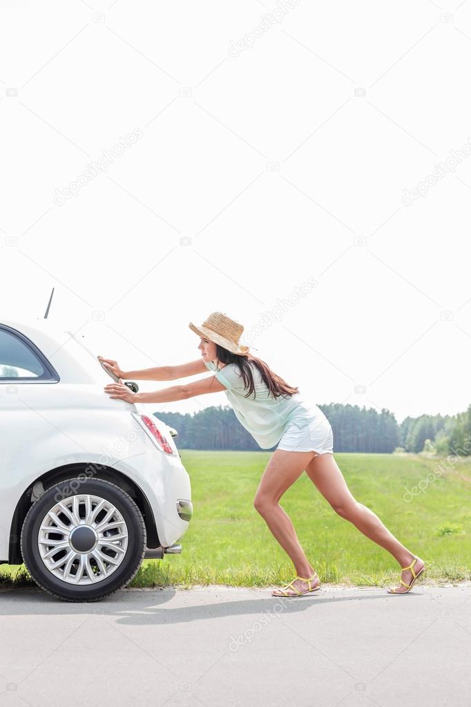 woman pushing broken down car