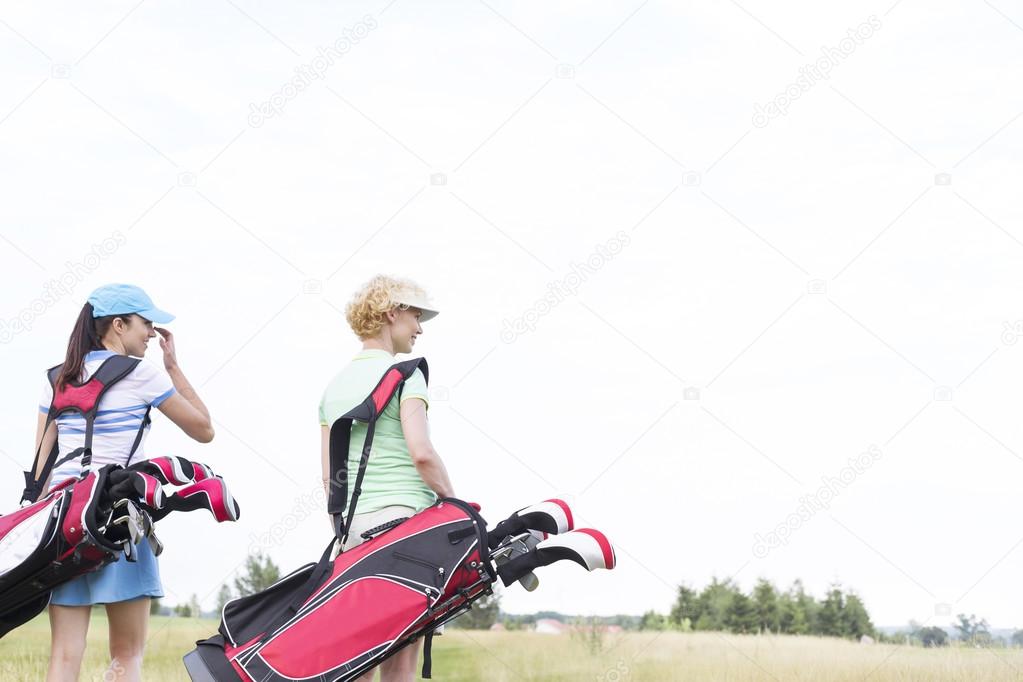 women with golf club bags walking