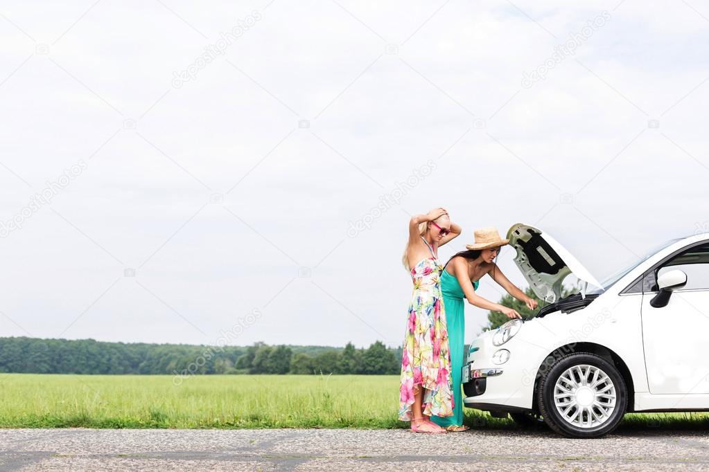 friends examining broken down car