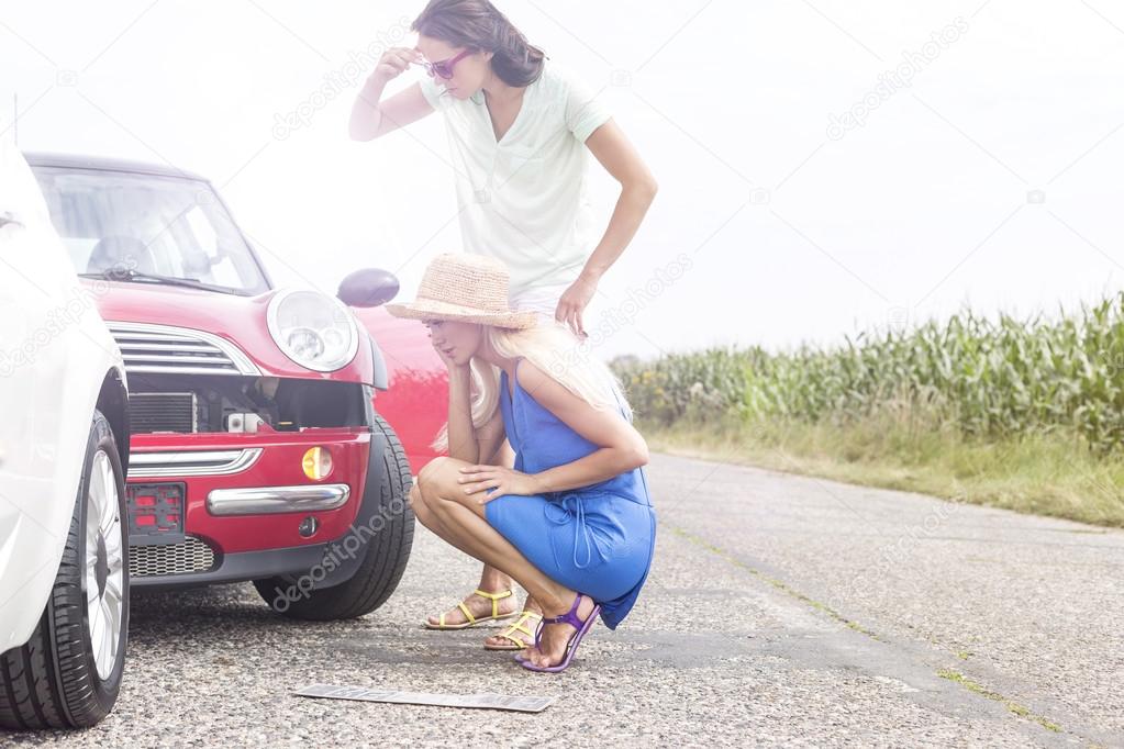 women looking at damaged cars