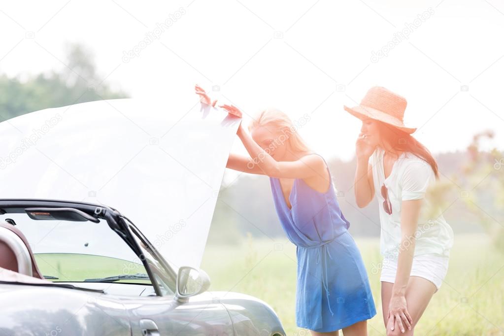 Friends examining broken down car